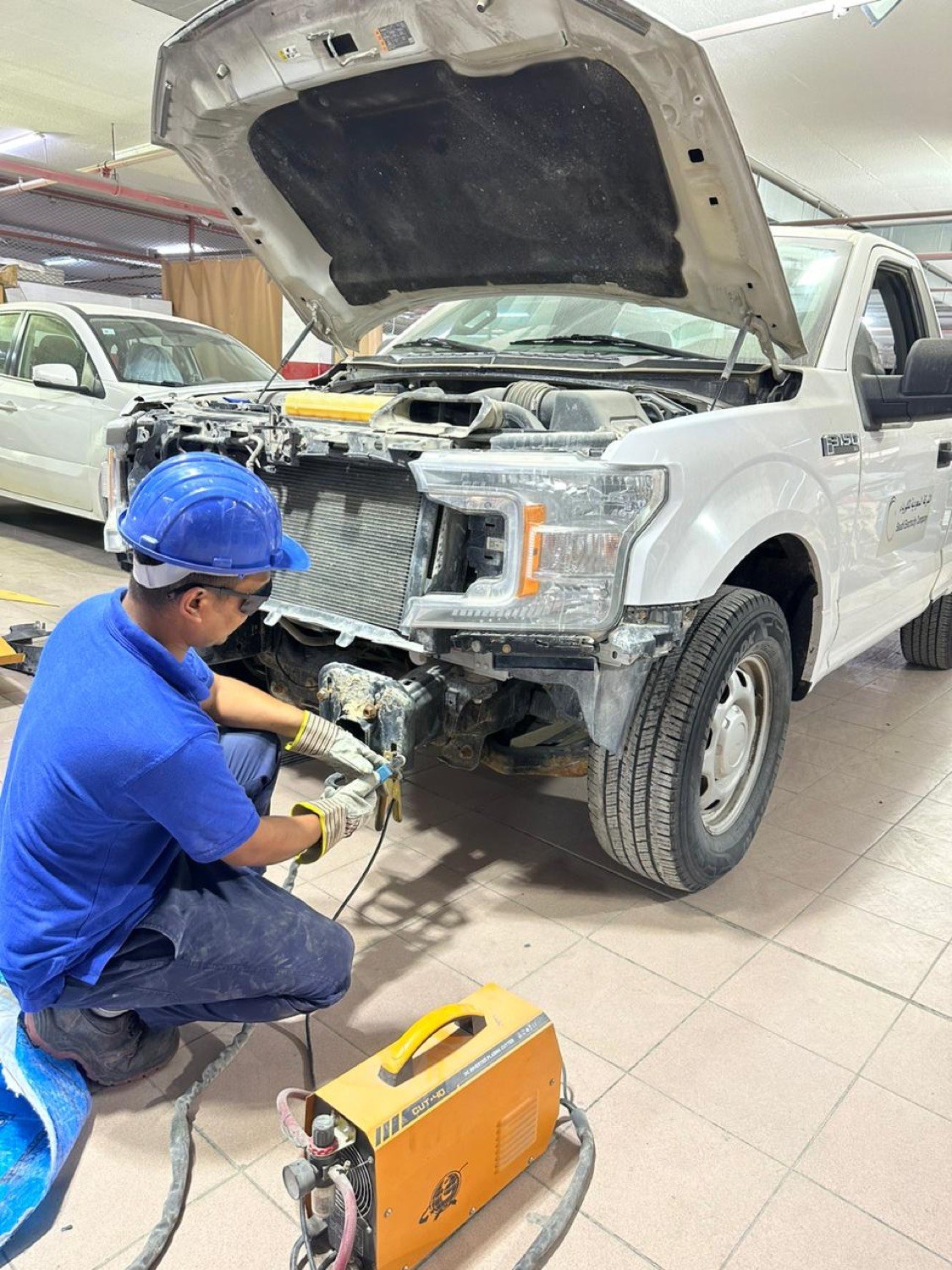 Technician repairing front body damage on a vehicle