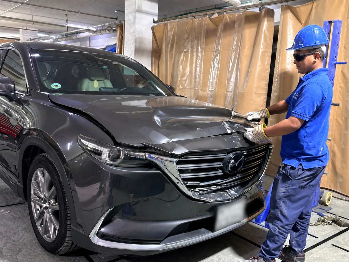Close-up technician panel repair work on a damaged vehicle front